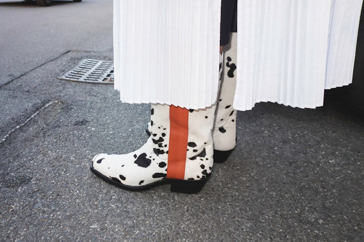 A close-up of a person wearing black-white cow-print boots at the Milan Fashion Week 2022