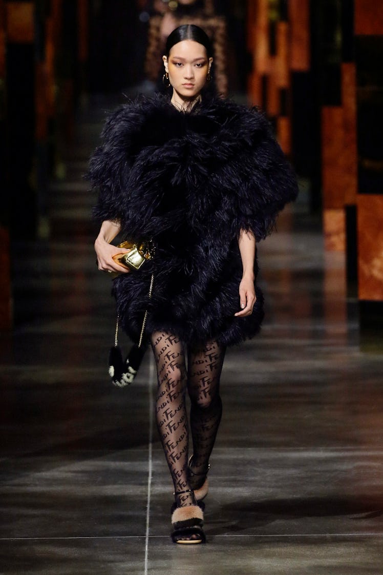 A model walking the runway at Milan Fashion week in a black feathered Fendi dress with black Fendi t...