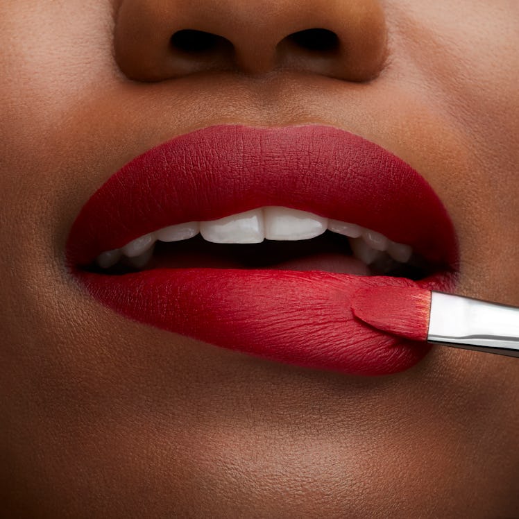 Woman applying MAC Cosmetic's Retro Matte Lipstick from its new Ruby's Crew collection.