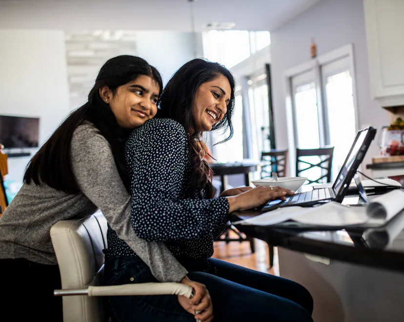 Woman working from home in kitchen while teenager daughter distracts her - stock photo