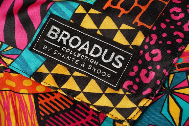 A closeup of a vibrant Broadus Collection scarf with the Broadus Collection by Shante & Snoop logo i...