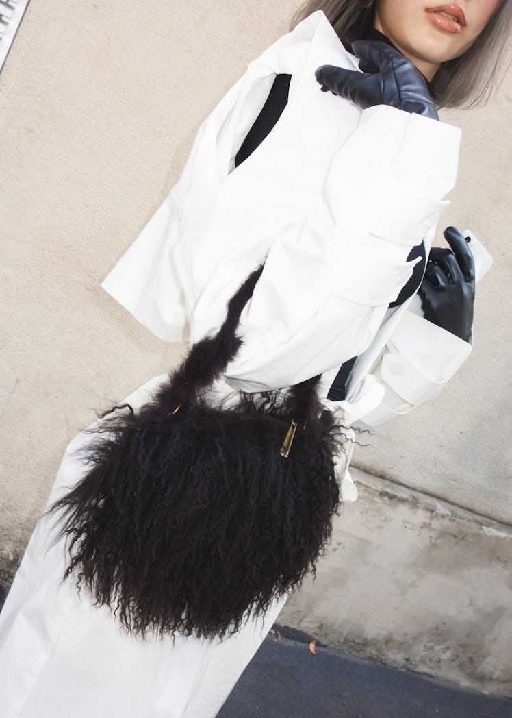 A woman in a white jacket and white trousers and a black bag at the Milano Fashion Week 2022