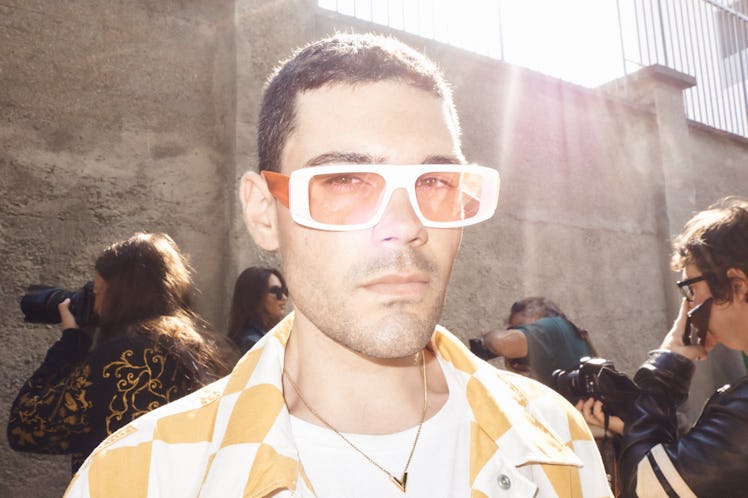 A man in white-orange sunglasses and a white-orange check shirt at Milan Fashion Week 2022