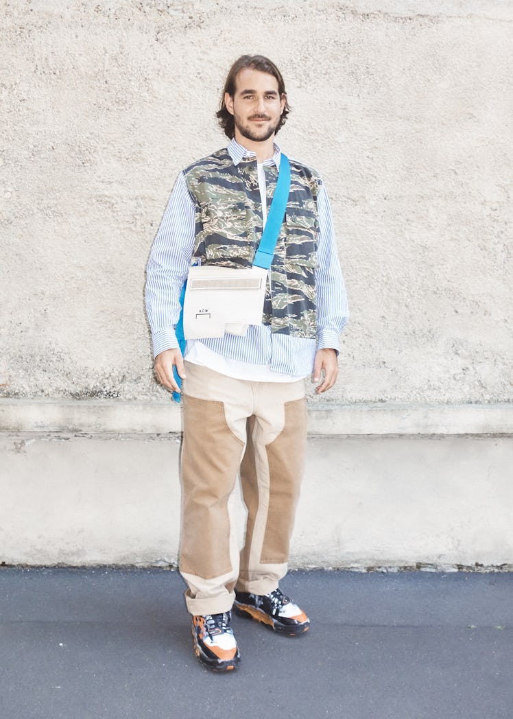 A man in a blue-camo print shirt, beige trousers and white-blue bag at the Milan Fashion Week 2022