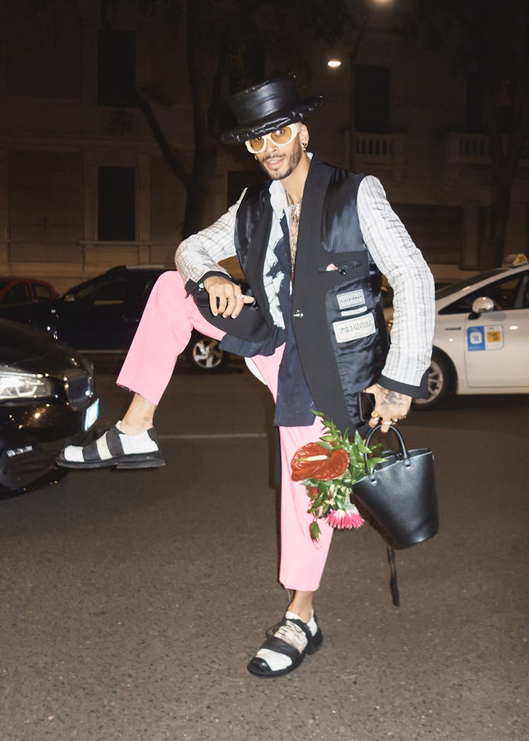 A man in a black-white blazer, pink trousers and a black hat at Milan Fashion Week 2022