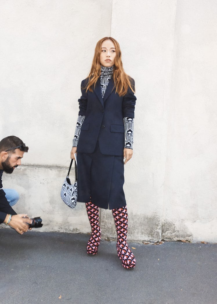 A woman in a navy skirt and blazer, a black-white turtle neck and matching bag at Milan Fashion Week...
