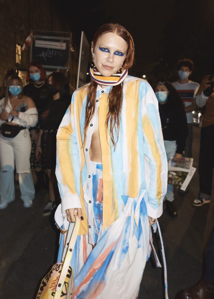 A woman in a hand-painted upcycled cotton shirt and trousers in white, yellow and blue