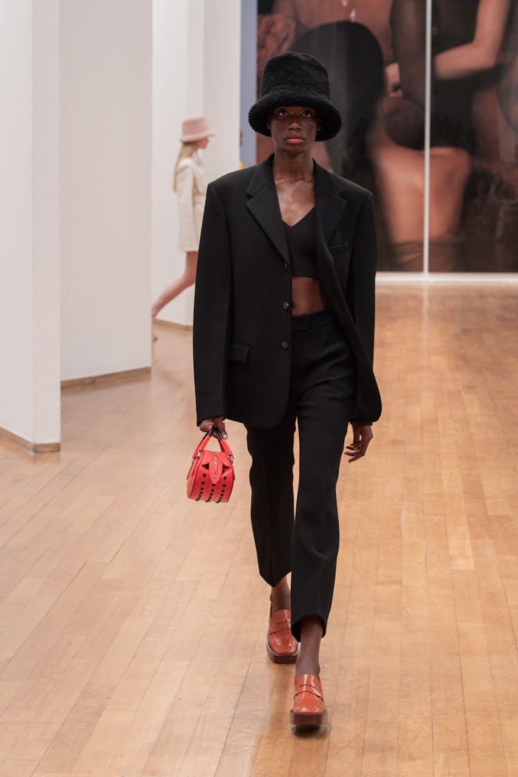 A model walking the Tod's runway at Milan Fashion Week Spring 2022 in a black suit with a bandeau un...