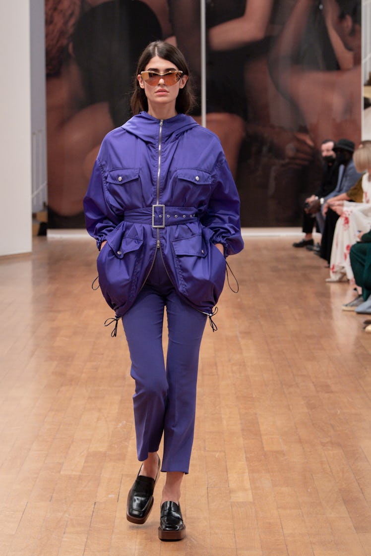 A model walking the Tod's runway at Milan Fashion Week Spring 2022 in a blue puffer coat and blue pa...