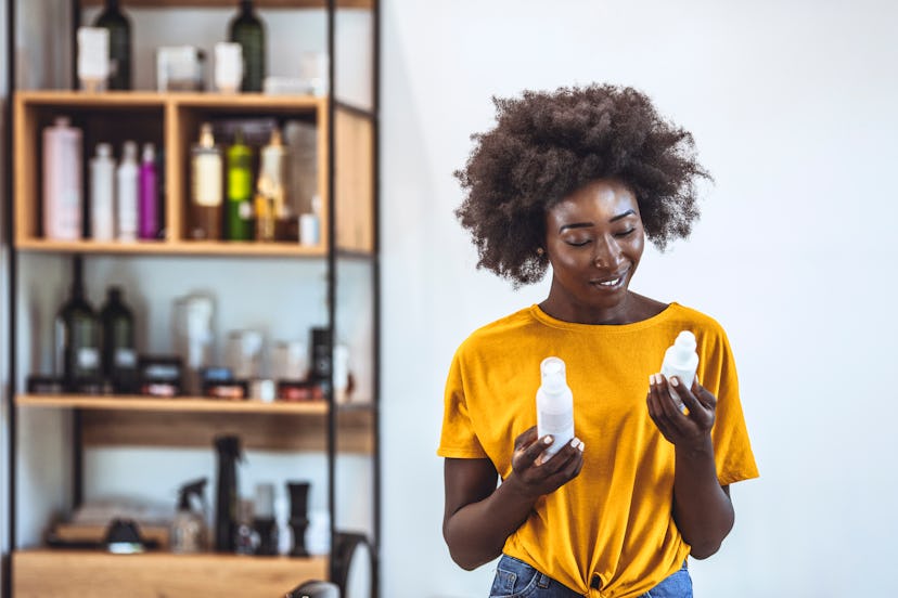 Woman holding two different products by a beauty product shelf