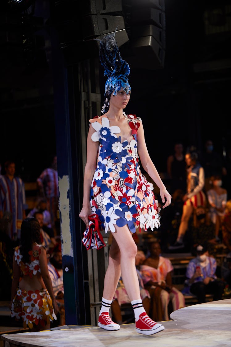 A model walking the runway in a Marni floral dress and red converse, along with a blue headpiece 