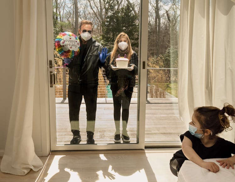 Two of Gillian Laub's family members standing outside her house with a cake and balloon for her birt...