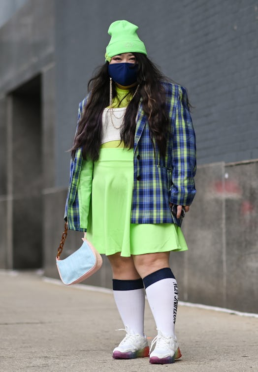 Scarlett Hao is seen wearing a bright green beanie, plaid jacket, green skirt and white sneakers out...