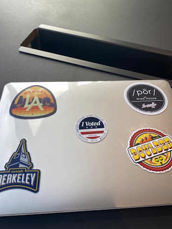 Laptop adorned with custom stickers from different WeWork office locations.