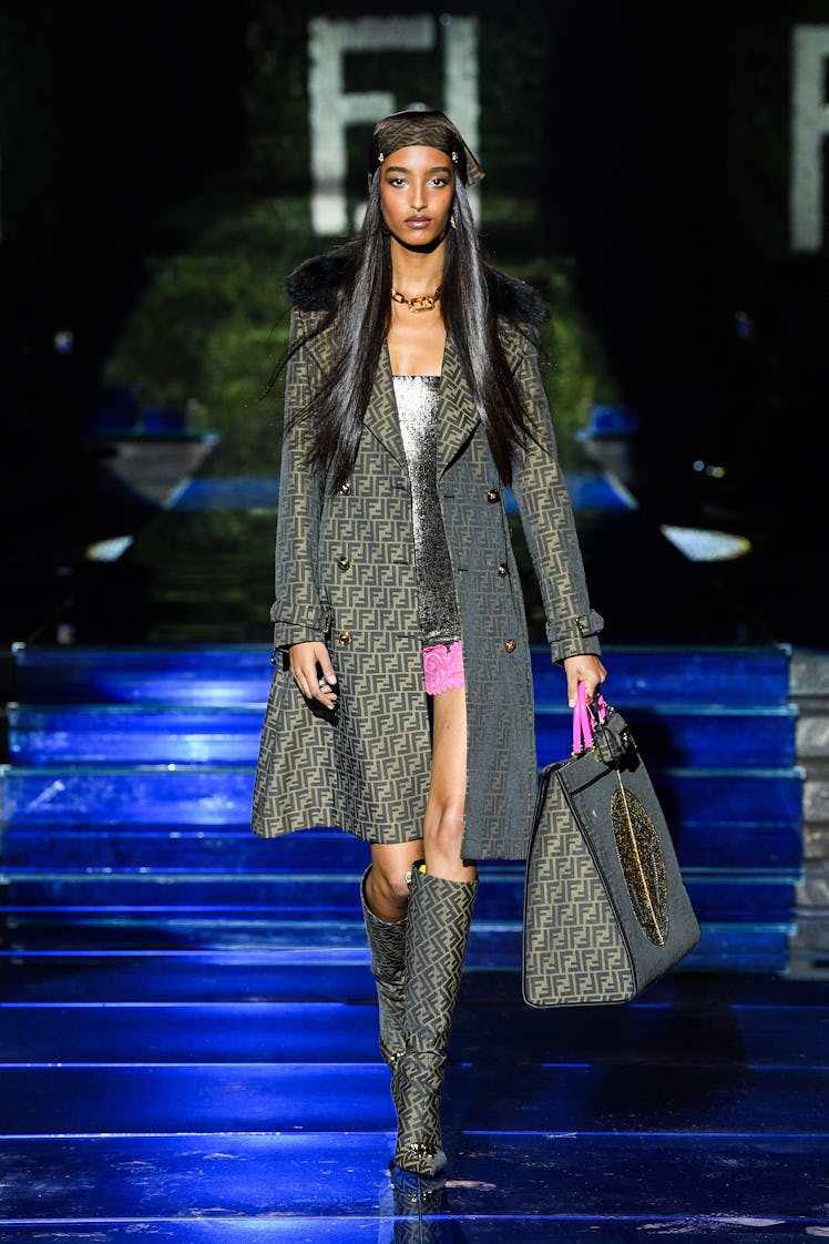 A model walking the runway in a grey Fendi by Versace jacket with a fur collar 