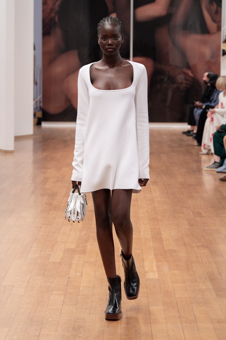 A model walking the Tod’s runway at Milan Fashion Week Spring 2022 in a white dress and black boots 