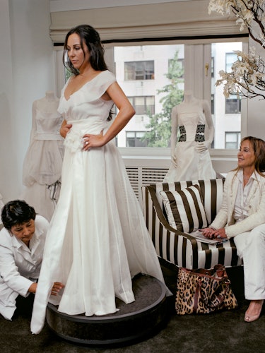 Gillian Laub at her wedding dress fitting with a woman sitting and admiring her as the tailor adjust...