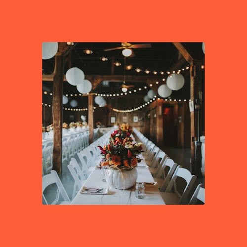 Dining room at a wedding venue with white chairs and tables and white lanterns hanging from above