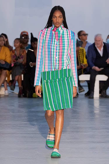A model Walking in a multi-colored check shirt and green skirt by Kenneth Ize