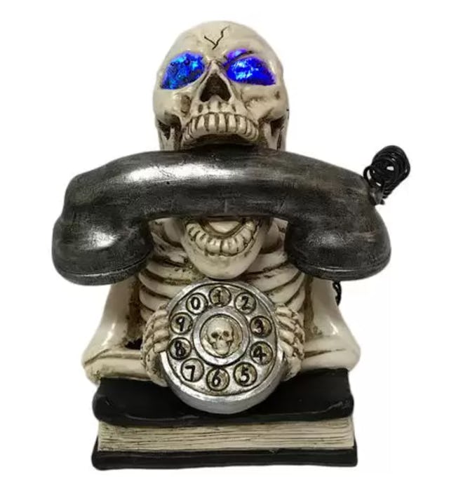 Halloween decor; skeleton holding phone, sitting on top of book