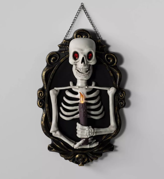Skeleton holding a candle; wall decoration