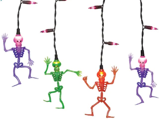 Four skeletons dangling from colorful icicle lights 
