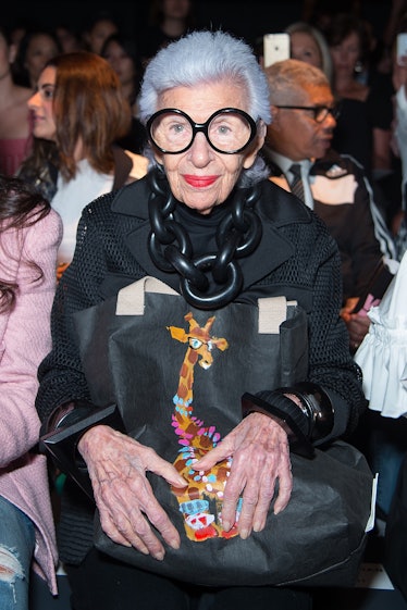 Iris Apfel clutching a bag with a giraffe motif