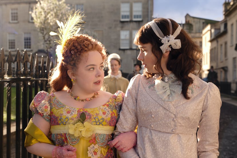 Eloise Bridgerton in a white ribbon headband and double-breasted dress walking arm-in-arm with Penel...