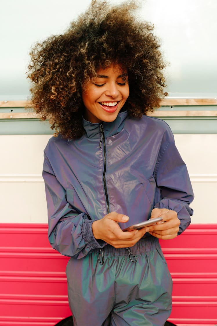 Stylish young woman wearing tracksuit and using cell phone to read her October 11, 2021 weekly horos...
