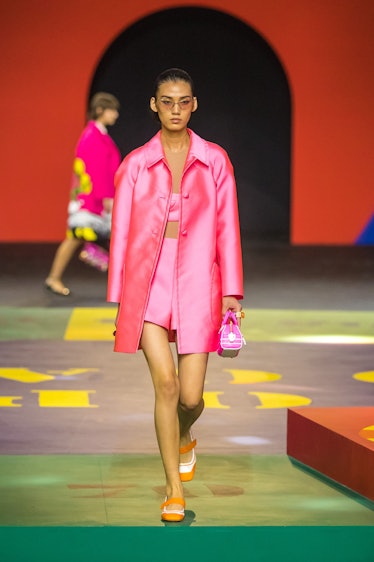 A model walking on the runway in a pink jacket, top and skirt by Dior
