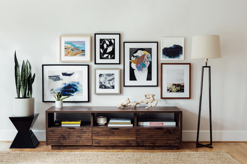 A stunning Gallery wall with various paintings in a room next to a 