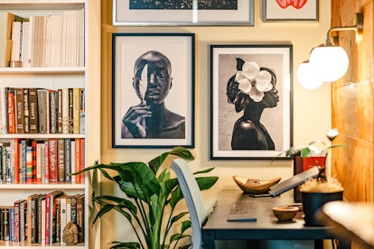 A stunning Gallery wall with various paintings in a room next to a desk with a chair