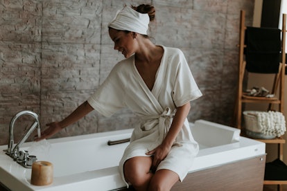 Woman preparing a bath in a robe
