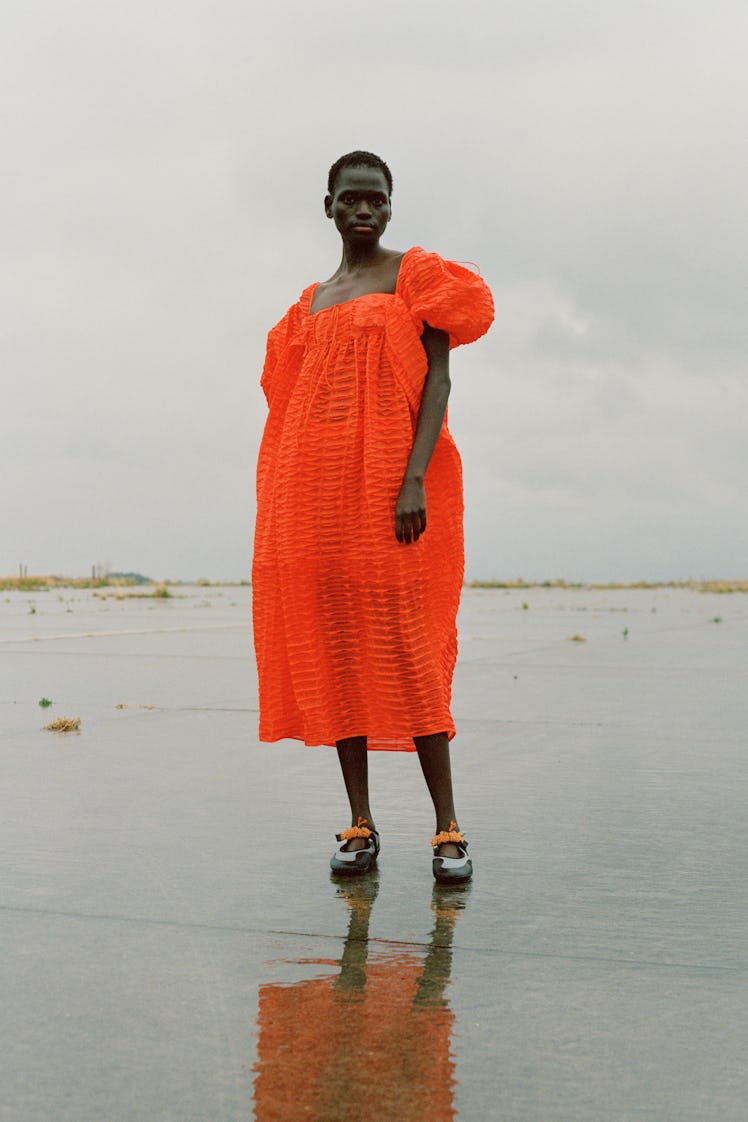 A model posing in an orange Cecilie Bahnsen Dress