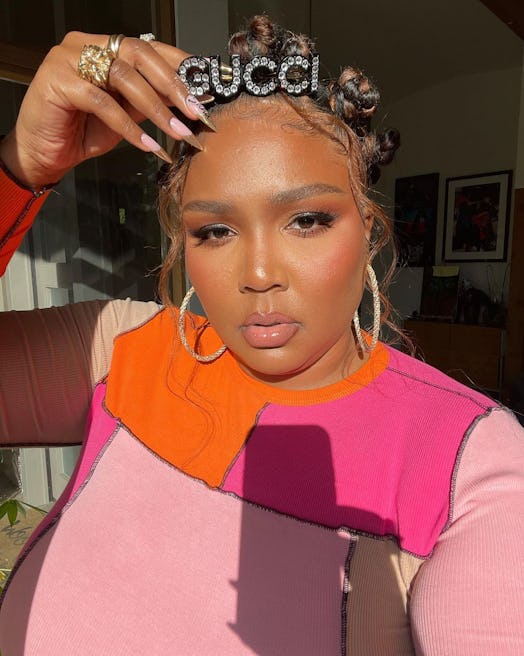 Lizzo posing with chrome nails, bantu knots, and gucci barrette 