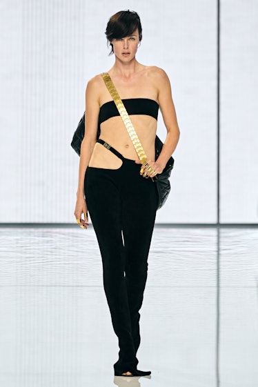 A model walking on a runway in a black top and pants by Balmain