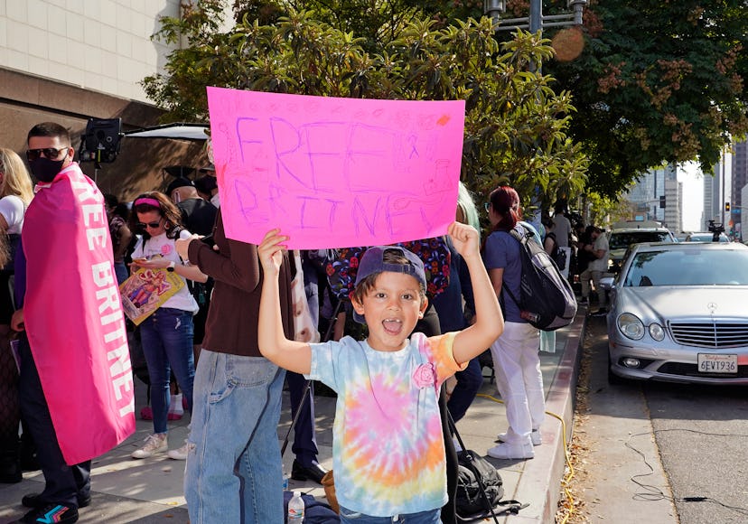 A little kid holding a "Free Britney" pink sign