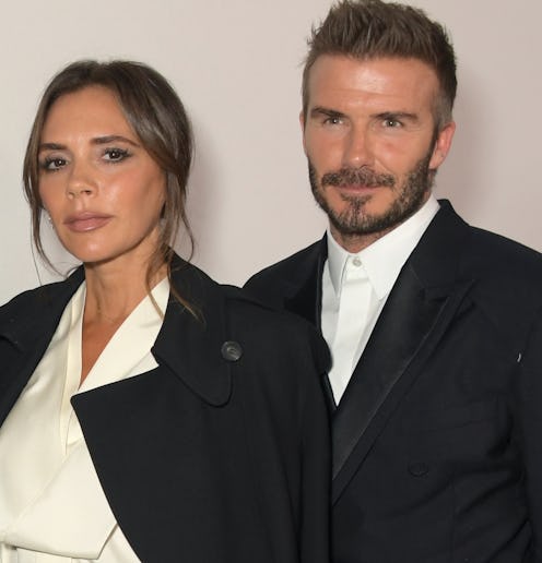Victoria Beckham and David Beckham. They are dressed smartly both wearing black trench coats and whi...