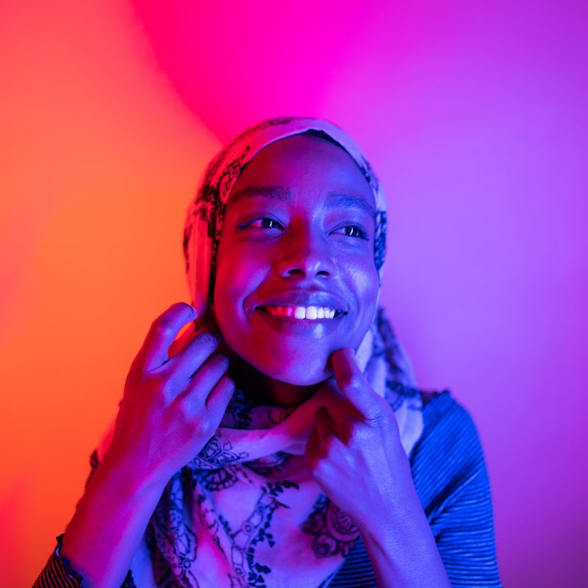 Smiling young woman in neon lights having the best week of September 13, 2021, per her zodiac sign's...