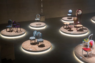 An array of chairs designed by artists in a dimly lit exhibition space