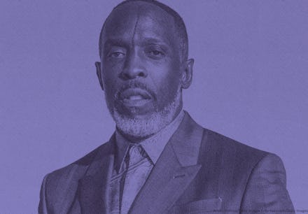 Michael K. Williams posing in a suit, with an orange background.