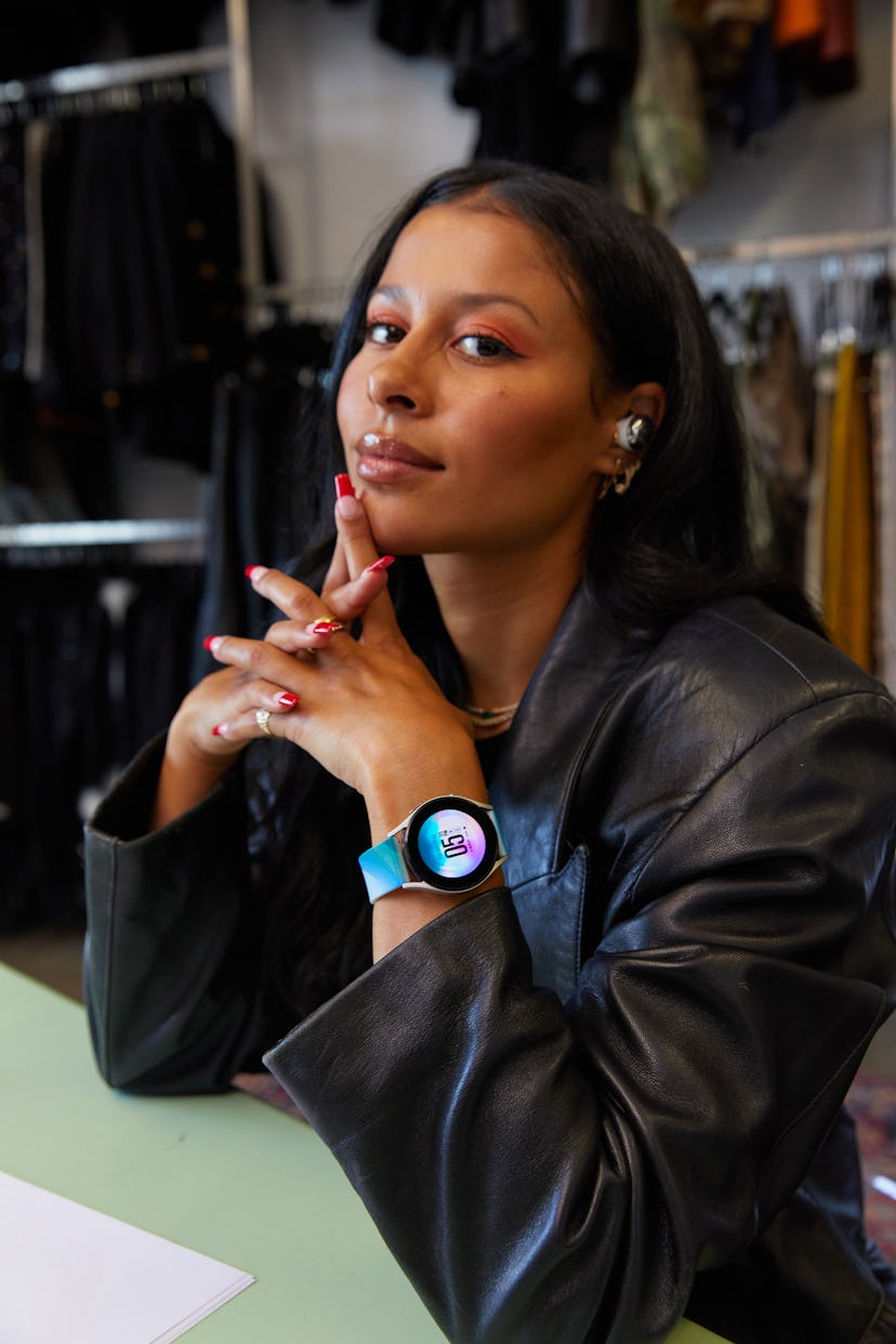 Sami Miró sitting with her fingers crossed in a clothing store for Samsung x Sami Miró Collection