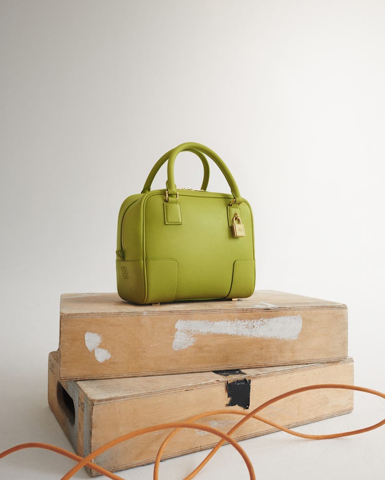 The Loewe Amazona bag in green, placed on two bricks 