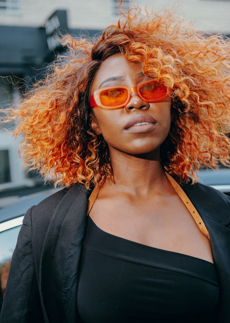Woman wears orange sunglasses