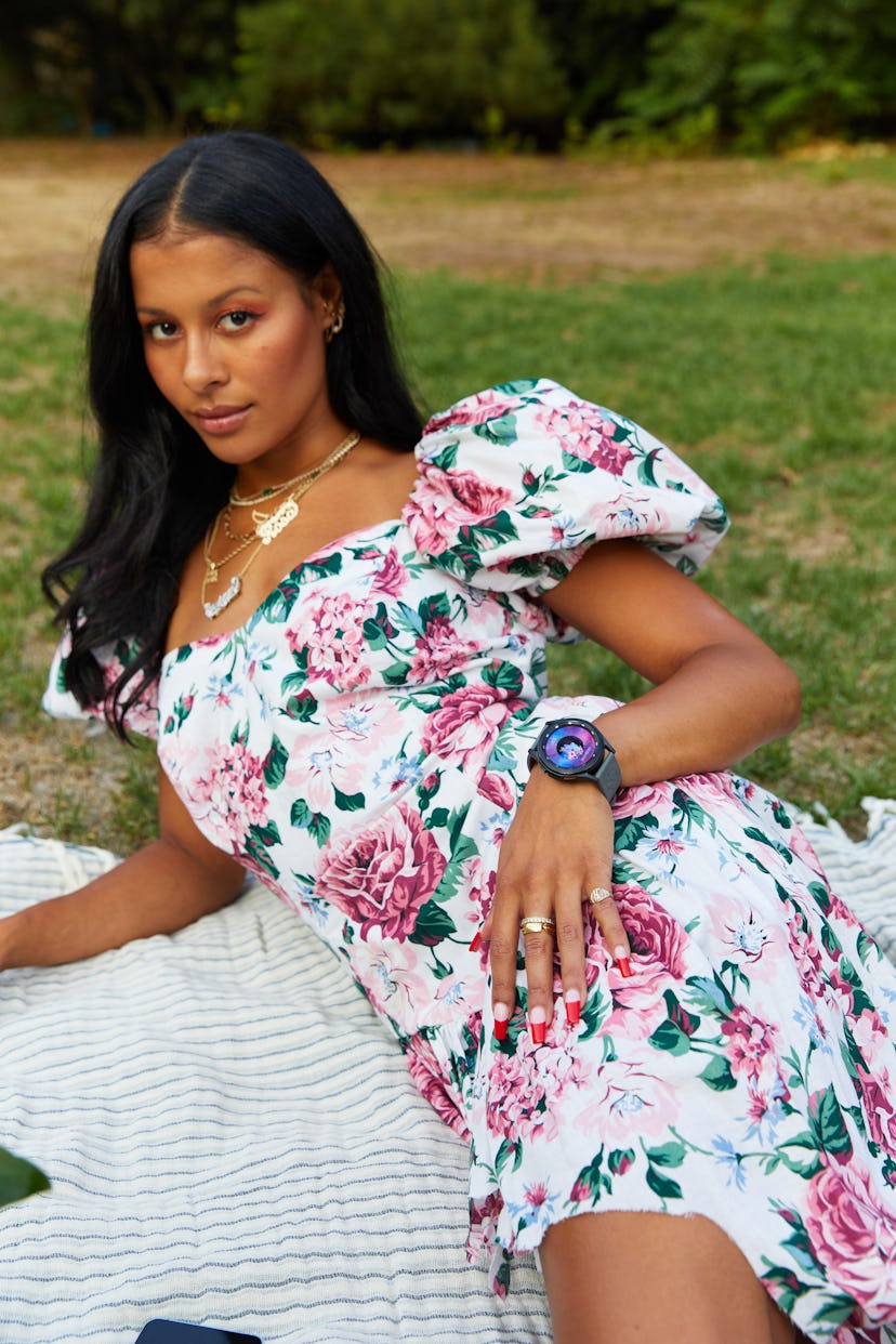 Sami Miró in a flowery dress lying on a blanket in the park for Samsung x Sami Miró Collection.