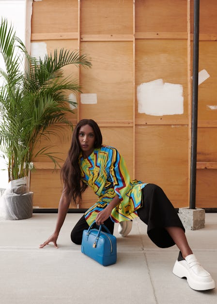 Ziwe Fumudoh crouching on the floor with a Loewe Amazona bag in blue 