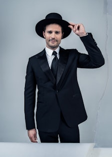 Jamie Dornan wears an Hermès tuxedo, shirt, and tie; Saint Laurent by Anthony Vaccarello hat.