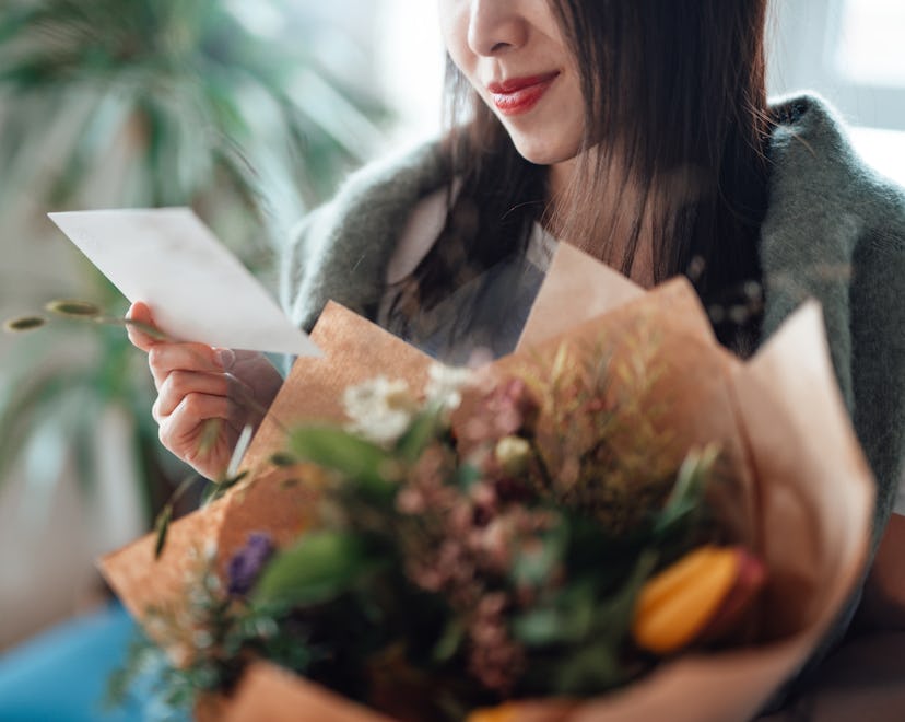 woman holding a bouquet of flowers, reading a handwritten note with a valentine's day poem for mommy