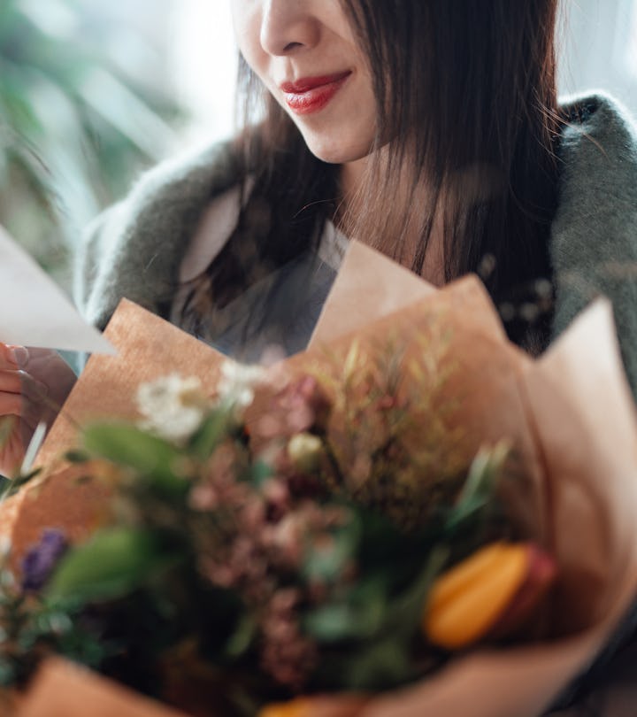 woman holding a bouquet of flowers, reading a handwritten note with a valentine's day poem for mommy