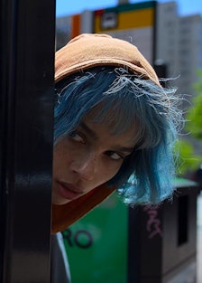 A blue-haired Zoë Kravitz peeking around a corner